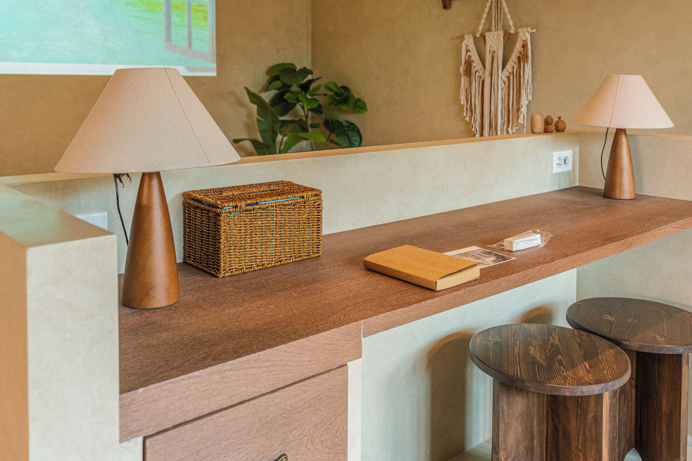 A wooden reception desk with two lamps, a wicker basket, and a book.