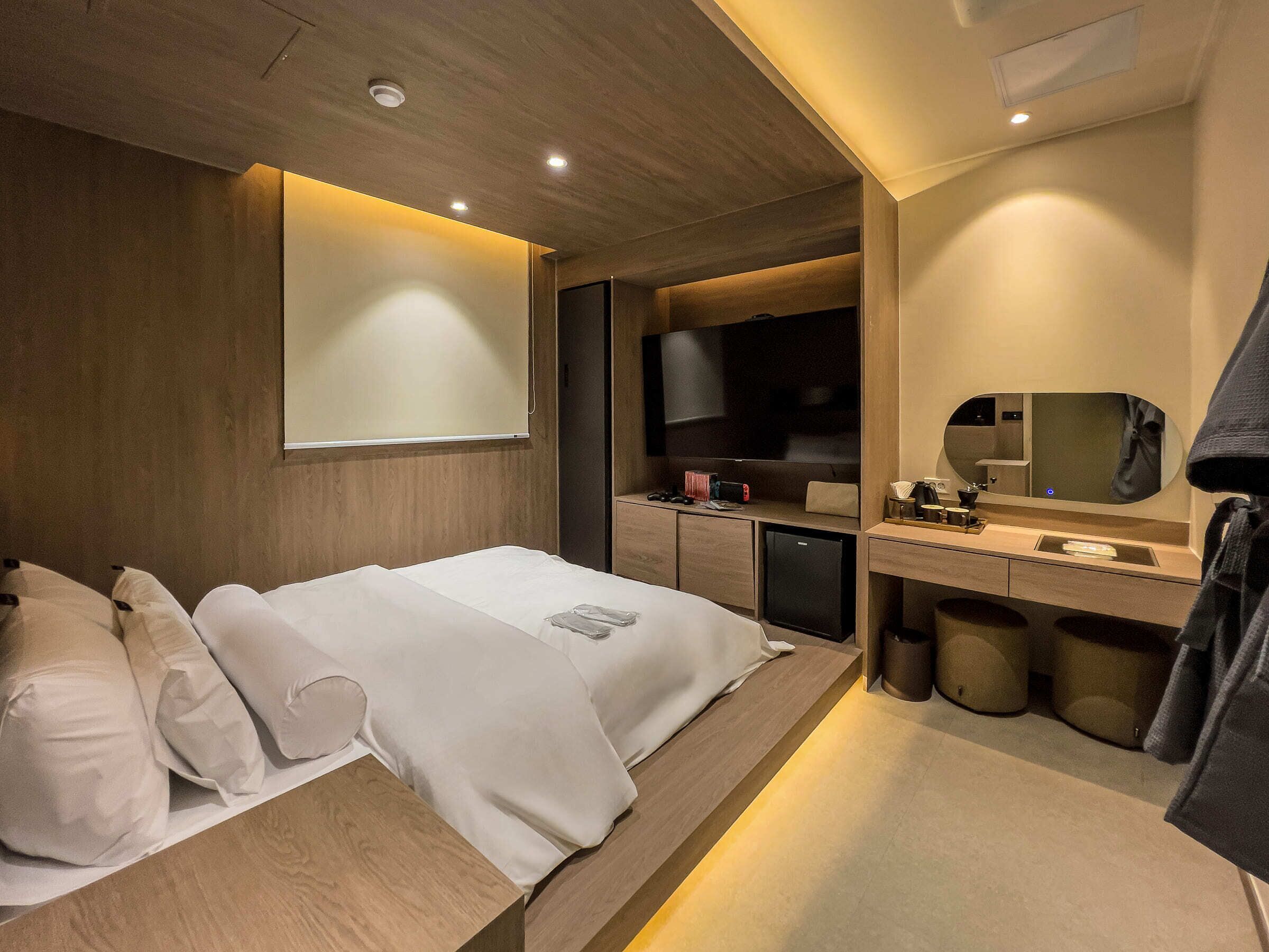 Una habitación de hotel moderna con cama, escritorio, televisor y baño.