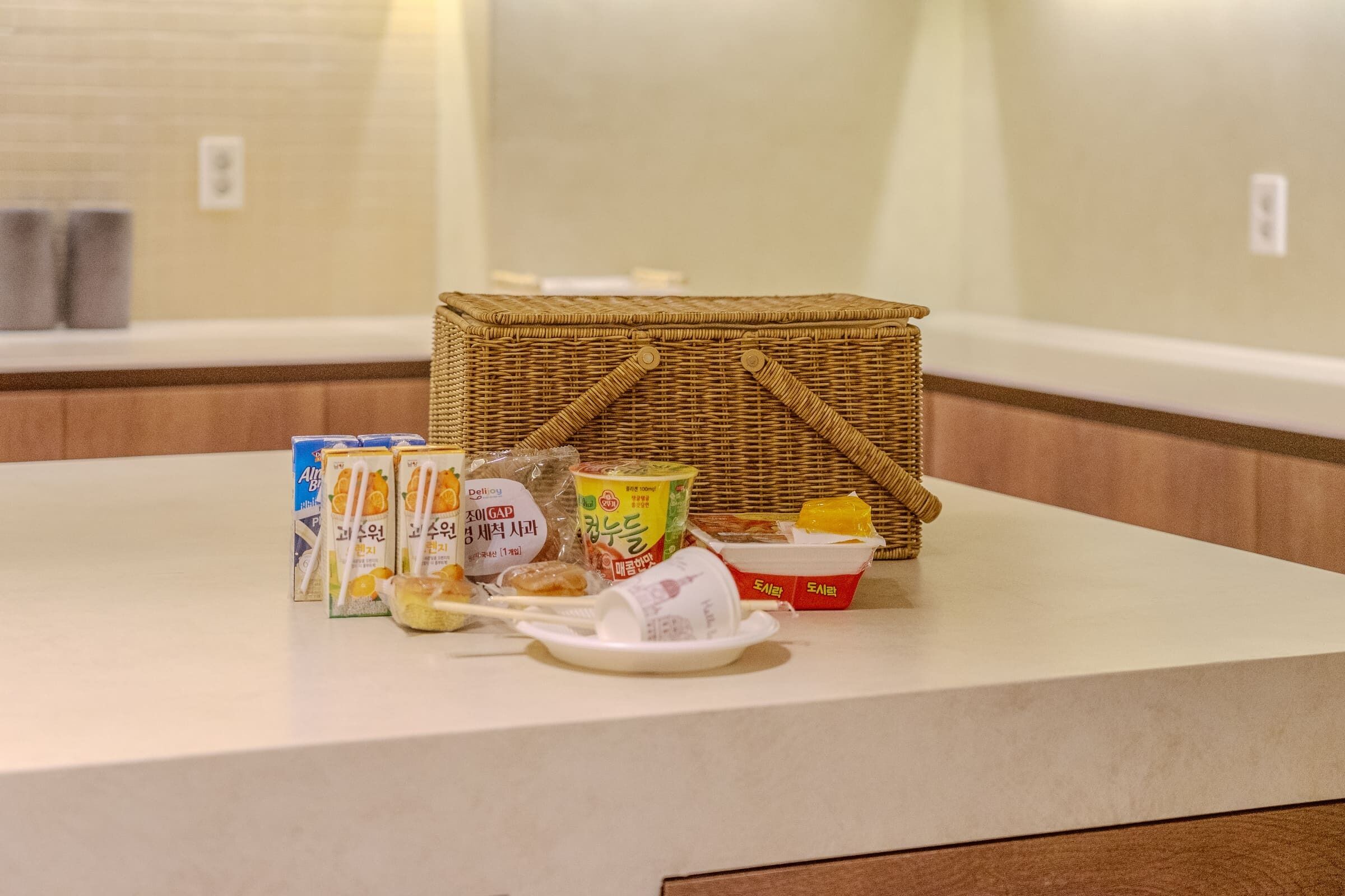 A breakfast setup with a wicker basket, a plate, and various food items on a counter.
