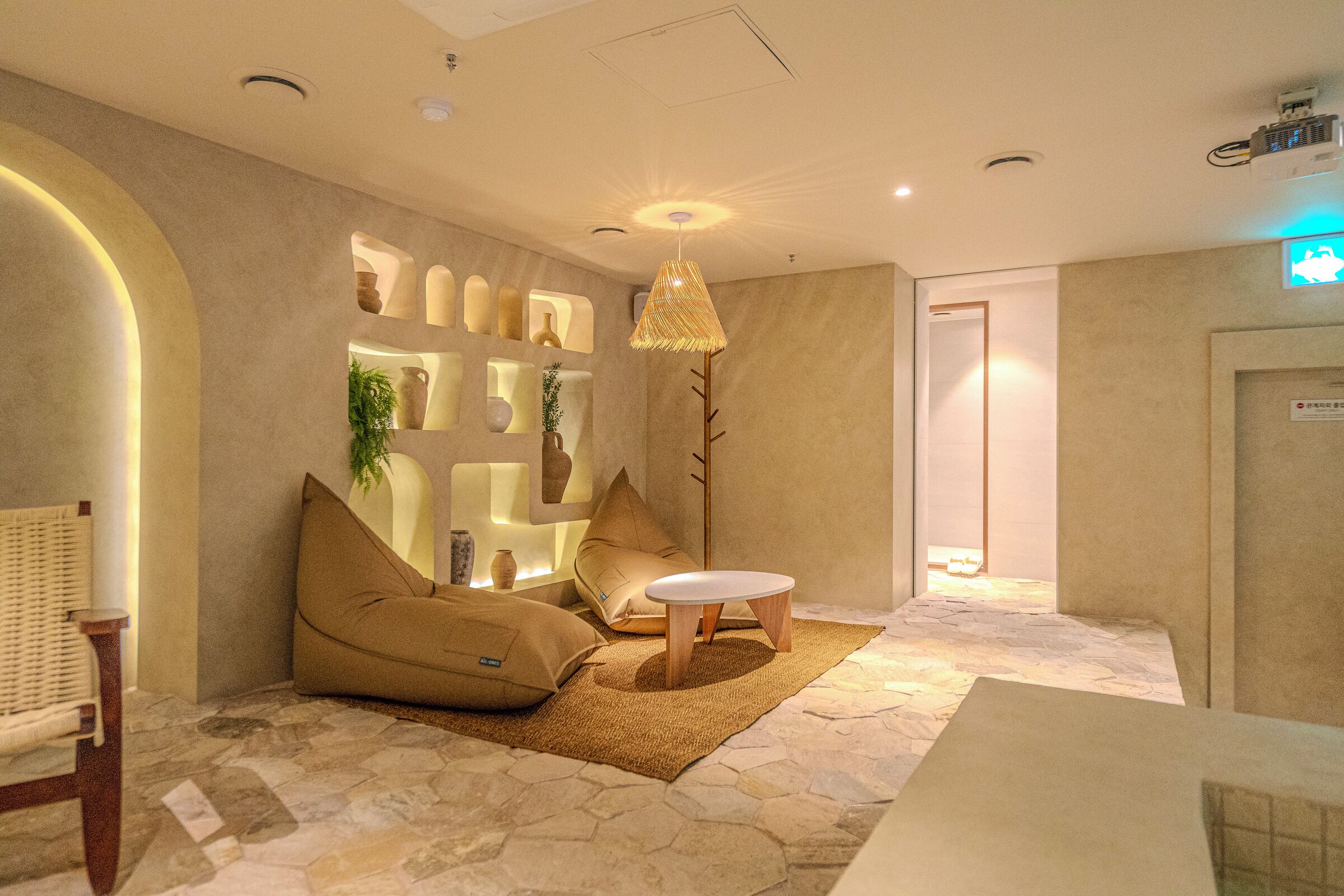 Een moderne hotel lobby met een zithoek, inclusief een bank en stoelen, een klein rond tafeltje en een decoratieve hanglamp.