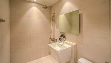 Un baño moderno con ducha, lavamanos e inodoro.