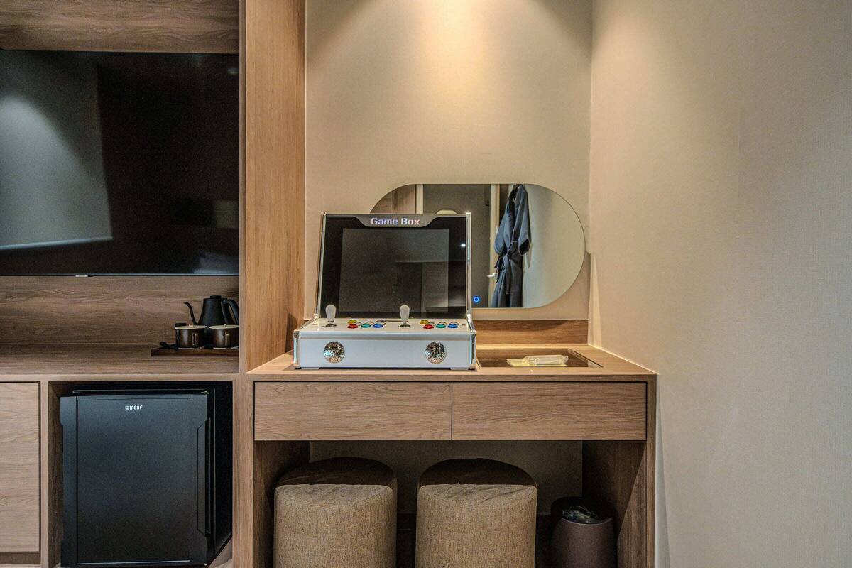 A compact room with a Game Box, a small refrigerator, and a mirror above a sink.