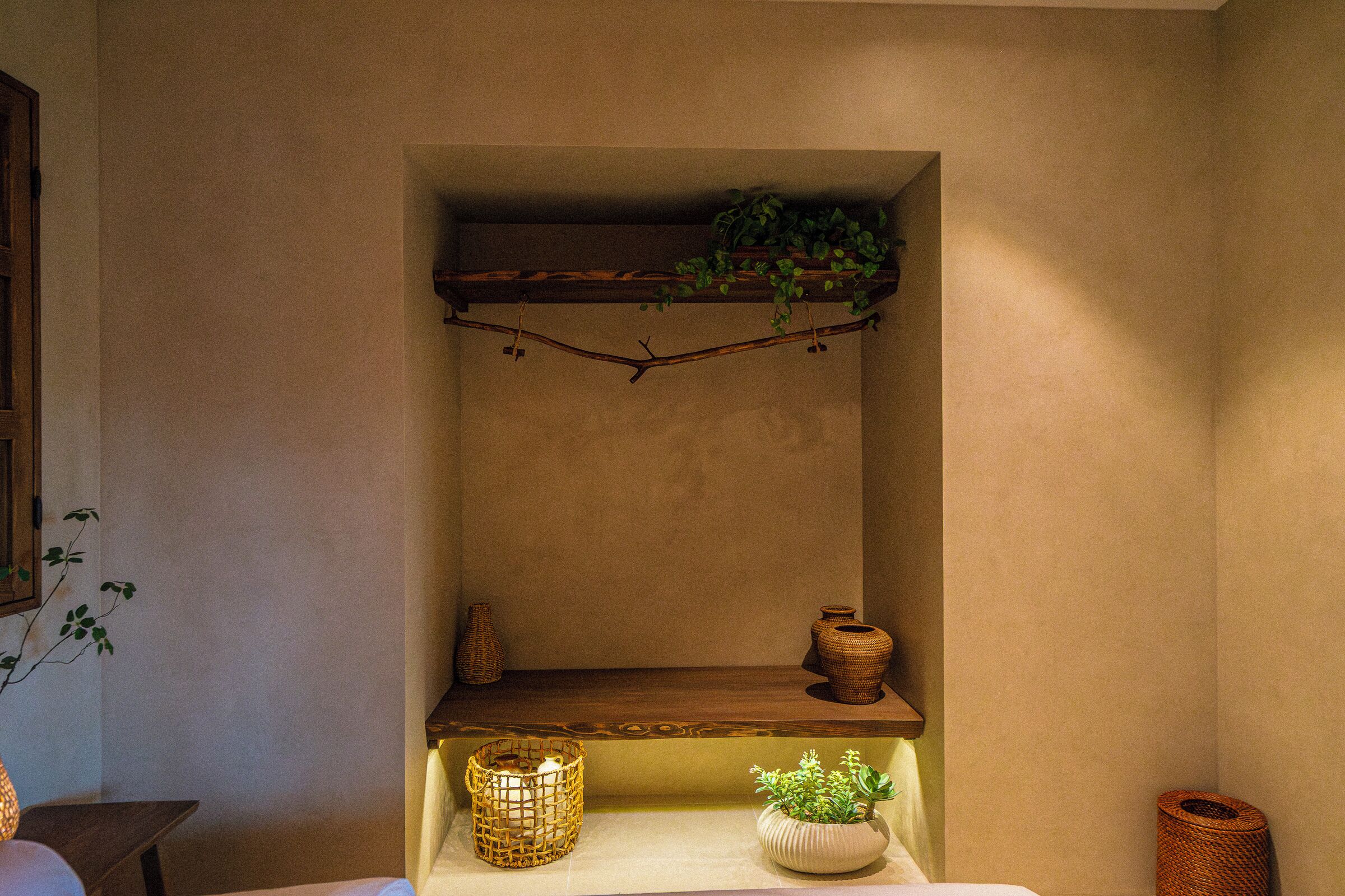 A shelf with a plant, two vases, and a candle holder.