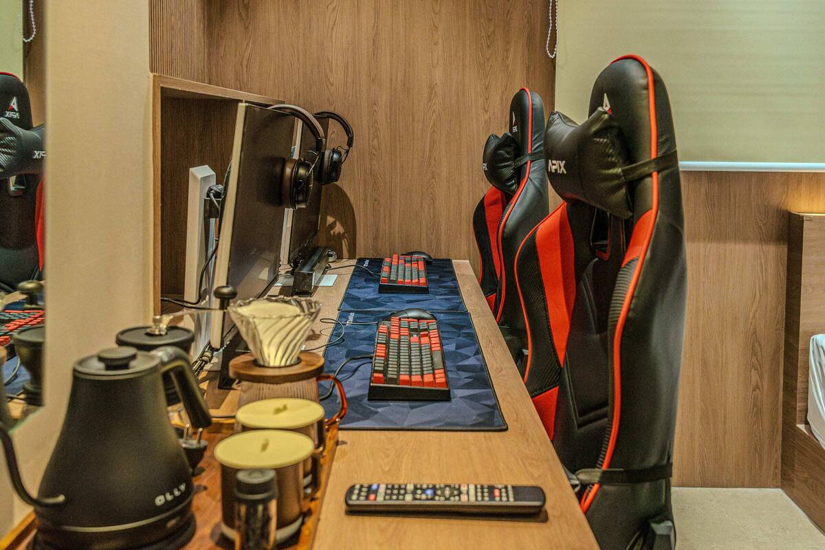 A gaming setup with multiple chairs, a long table, and various gaming peripherals.