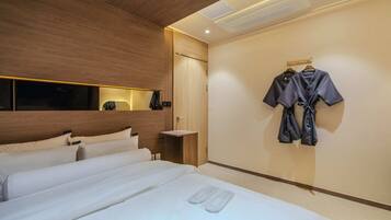 Habitación de hotel con una cama grande, cabecera de madera, mesita de noche y perchero en la pared.
