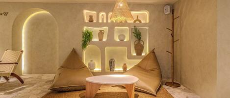 A modern living room with a round coffee table, two beige sofas, a hanging light fixture, and built-in shelves with decorative items.