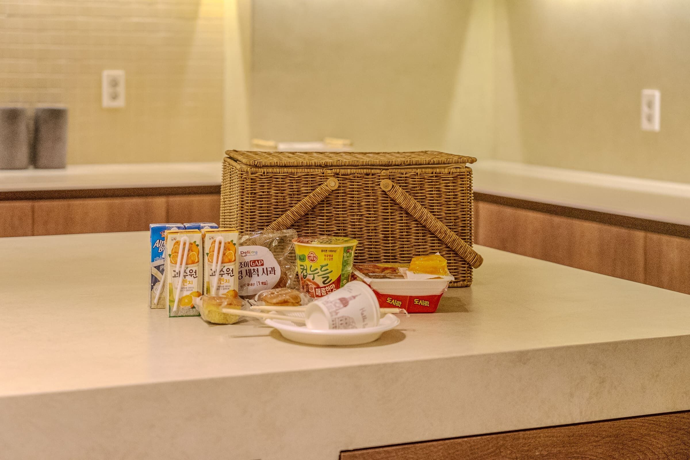 A breakfast setup with a wicker basket, a plate with food, and various packaged items on a counter.