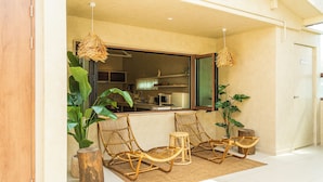A room with a kitchen area, two wicker chairs, a small table, and large potted plants. - Maison de On U Hotel Gwangju cheomdan (Gwangju)