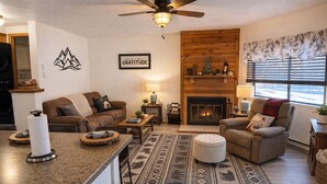 A cozy living room with a fireplace, a ceiling fan, and a 'Gratitude' sign on the wall. - Escape to Tranquility at Mountain Top Condo! (Somerset)