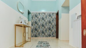A hallway with a patterned wallpaper, a gold console table, and a chandelier. - "Enchanted Home" Independent and close to the center of Civitavecchia- Rome (Civitavecchia)