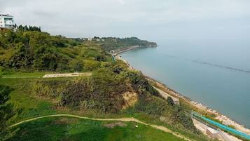 Paesaggio costiero con un sentiero pedonale, un ponte e una costa in lontananza.