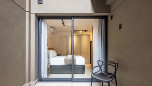 Une chambre d’hôtel avec un lit, une chaise et une porte-fenêtre coulissante donnant sur un couloir.