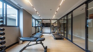 Une salle de sport équipée de tapis de course, d’haltères et de bancs.