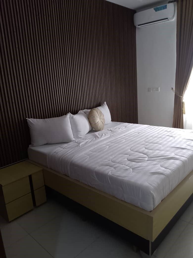 Um quarto moderno com uma cama, mesas de cabeceira e um aparelho de ar condicionado.