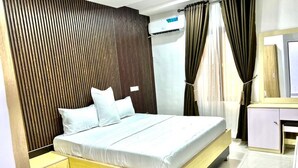 Un dormitorio moderno con una cabecera de madera con listones, una cama con ropa blanca, una mesita de noche, un armario y un espejo.