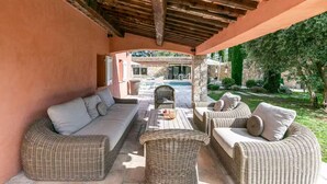 An outdoor patio with wicker furniture, a pool, and a stone wall. - Magnificent Villa near Fayence (Saint-Paul-en-Forêt)