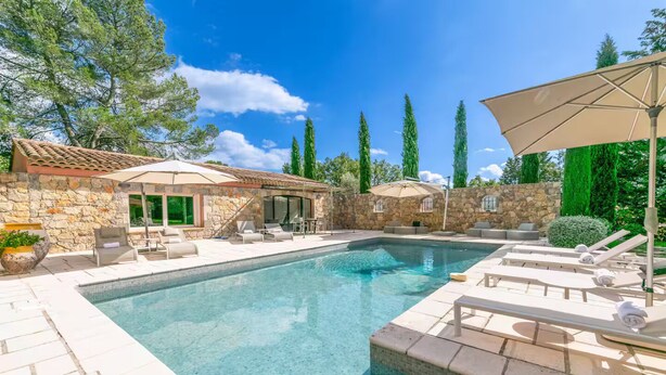 A swimming pool with lounge chairs and umbrellas, surrounded by stone walls and greenery. - Magnificent Villa near Fayence (Saint-Paul-en-Forêt)