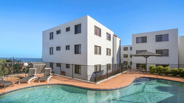 Un edificio moderno con piscina y zona de estar exterior.