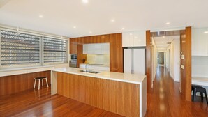 A modern kitchen with wooden cabinetry, a white countertop, and stainless steel appliances. - Hume Parade 19, Unit 1, Currimundi (Currimundi)