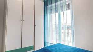 A bedroom with a bed, a wardrobe, and a window with curtains.