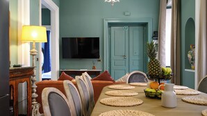 A dining area with a table set for four, surrounded by chairs. A television is mounted on the wall above the table. - [5 Bedrooms, 3 bathrooms] Historic residence in Coliseum (Roma)