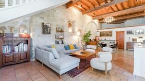 Un salón amplio con sofá, sillones, una mesa de centro y una estantería.