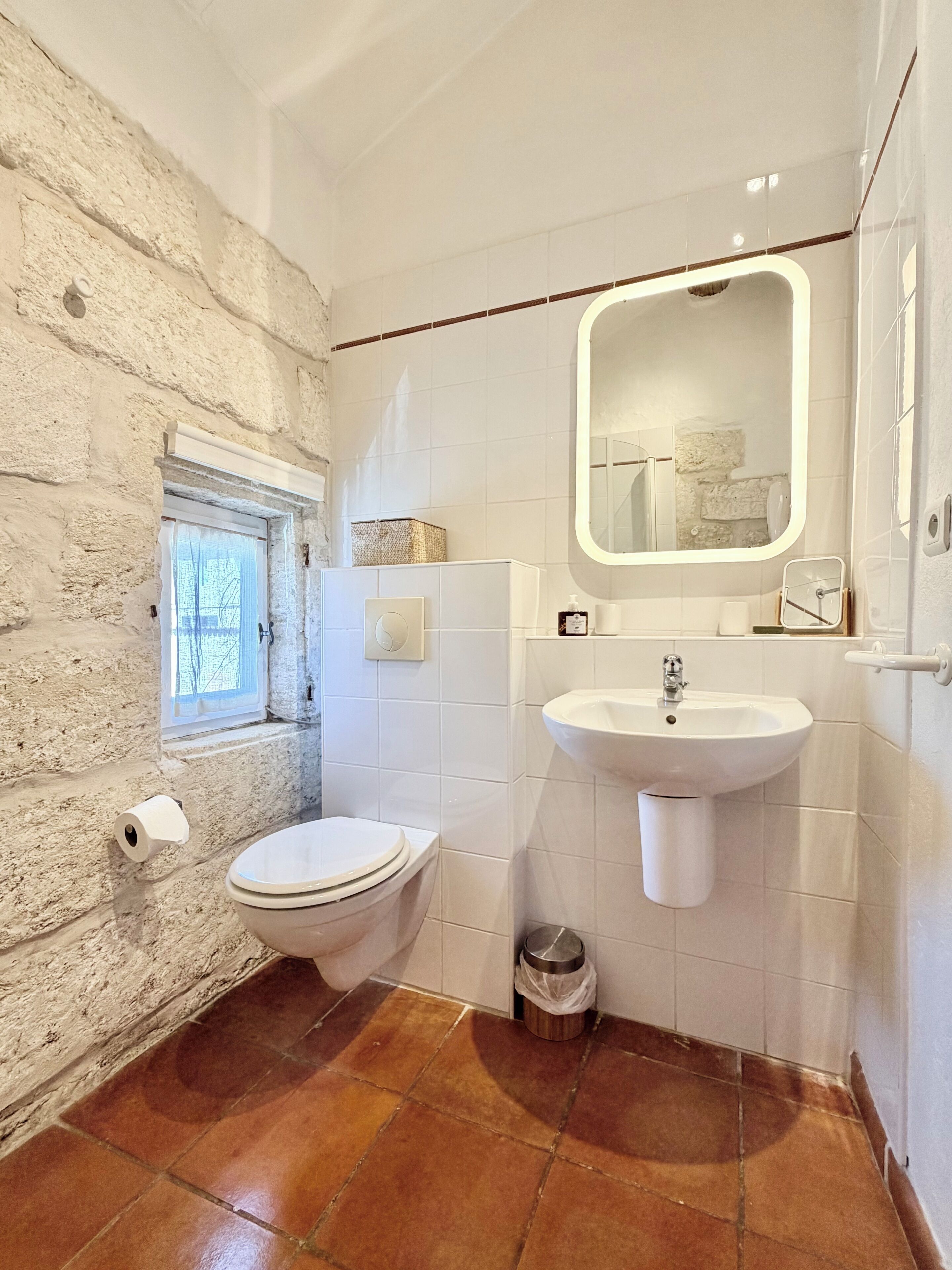Une salle de bain avec des toilettes, un lavabo et une fenêtre.
