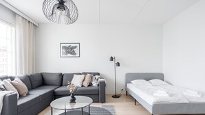 A modern living room with a grey sofa, a round coffee table, a grey bed, and a floor lamp. - Lakefront Home near Downtown (Jyväskylä)
