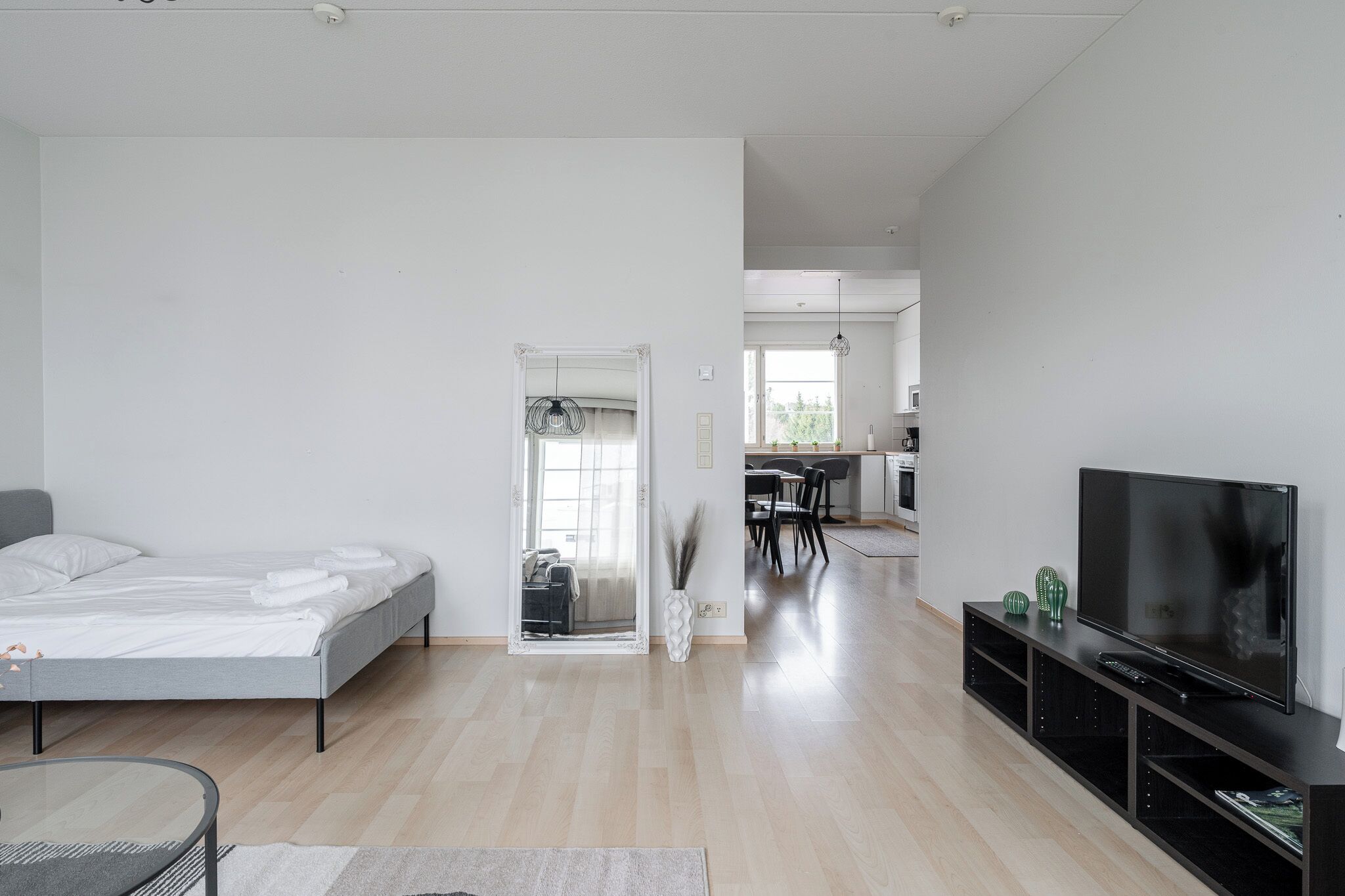 A modern living room with a bed, TV, and dining area.