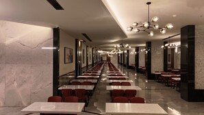 A long corridor with tables and chairs, marble walls, and modern lighting fixtures. - Ajm Mina Hotel (Makkah)