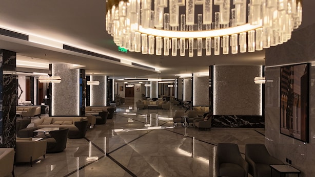 A spacious lobby with a high ceiling, modern chandeliers, and a mix of seating areas including sofas and armchairs. - Ajm Mina Hotel (Makkah)