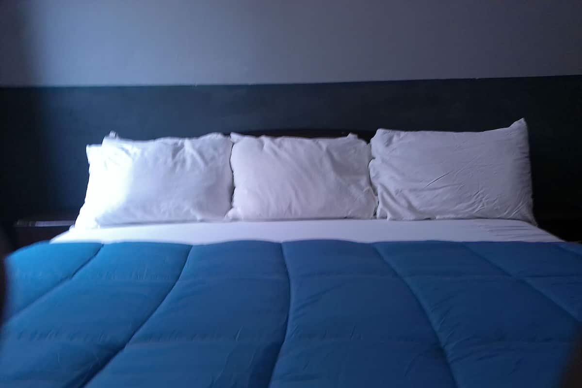 A bed with a blue cover and white pillows.