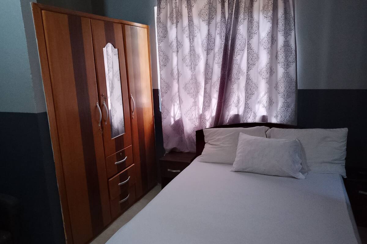 A bedroom with a bed, a wardrobe, and curtains.