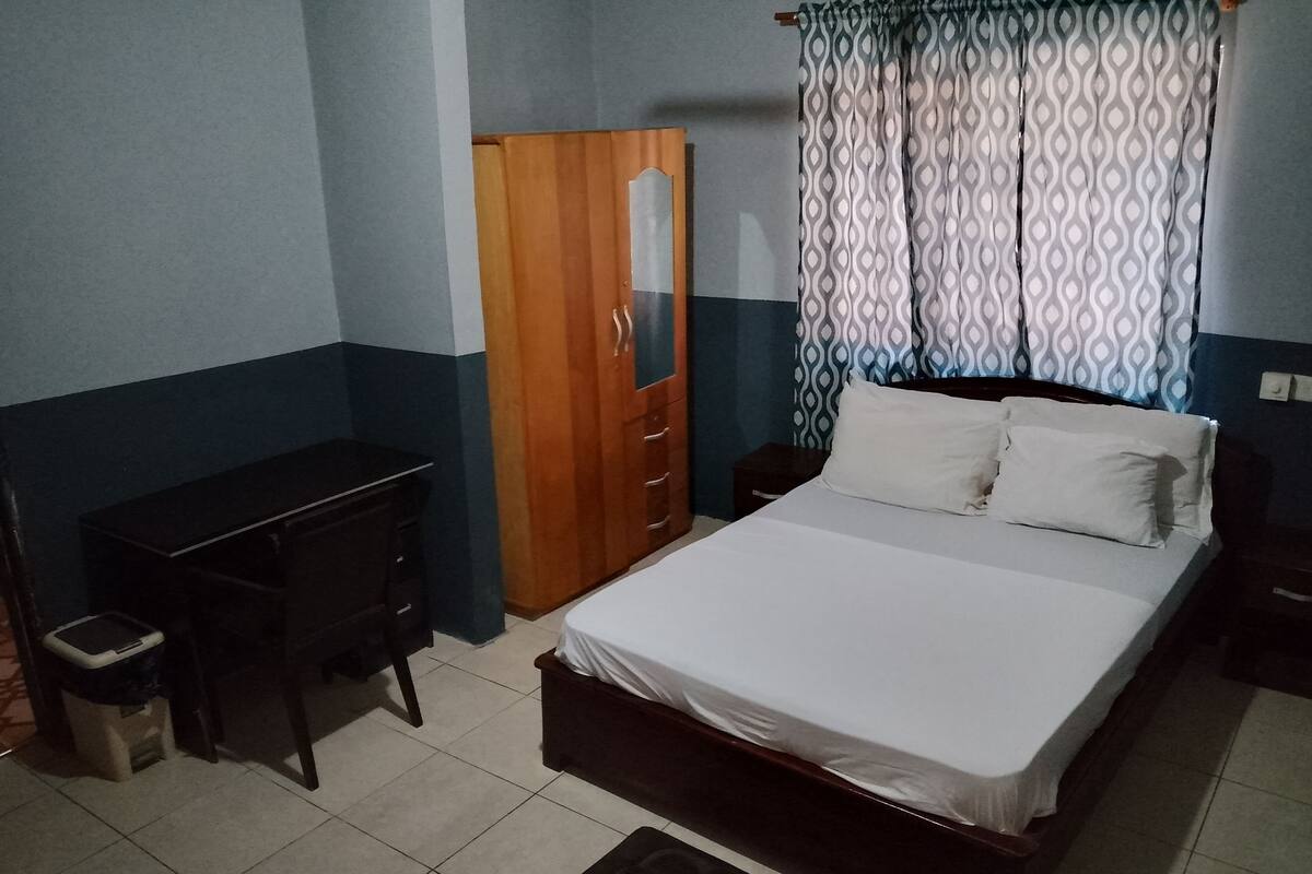A bedroom with a bed, a desk, and a wardrobe.