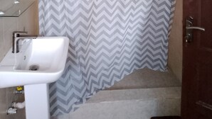 A bathroom with a shower curtain, a sink, and a door. - Great Escape Inn Hotel  (Weija)