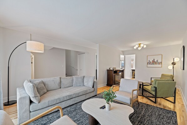 A modern living room with a grey sofa, a coffee table, and a green armchair.