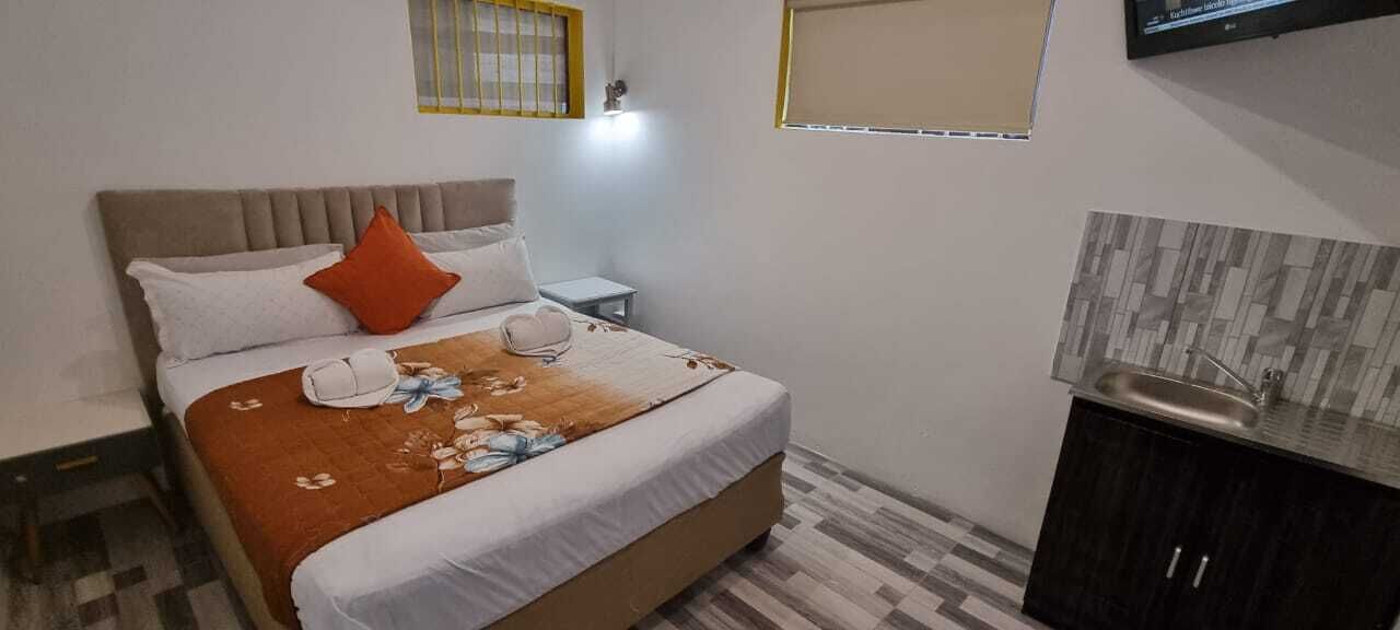 Ein Schlafzimmer mit einem Bett, Kissen, einem Nachttisch, einem Fernseher und einem kleinen Schrank.