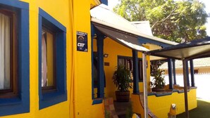 A yellow building with blue trim, a covered porch, and potted plants. - Neo & ruks guest house Boston (Cape Town)