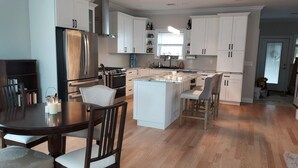 A modern kitchen with white cabinets, a central island, and a dining area with a round table and chairs. - Tranquil lakefront oasis - close to NYC and NJ attractions (Watchung)