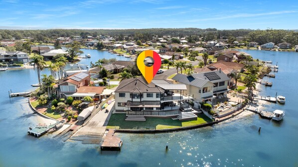A waterfront property with a large house, dock, and boats. - Riverside Manor (Sussex Inlet)