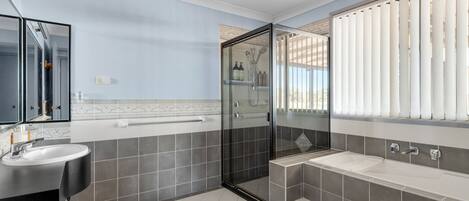 A modern bathroom with a glass-enclosed shower, a vanity with a sink, and a bathtub.