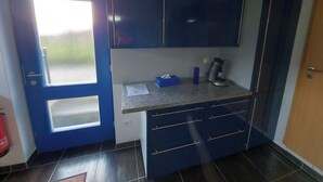 Une cuisine de taille réduite avec des meubles de couleur bleu foncé, un plan de travail en granit et un petit évier.