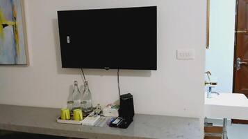 Un televisor de pantalla plana montado en una pared sobre una encimera con un lavabo y una puerta.