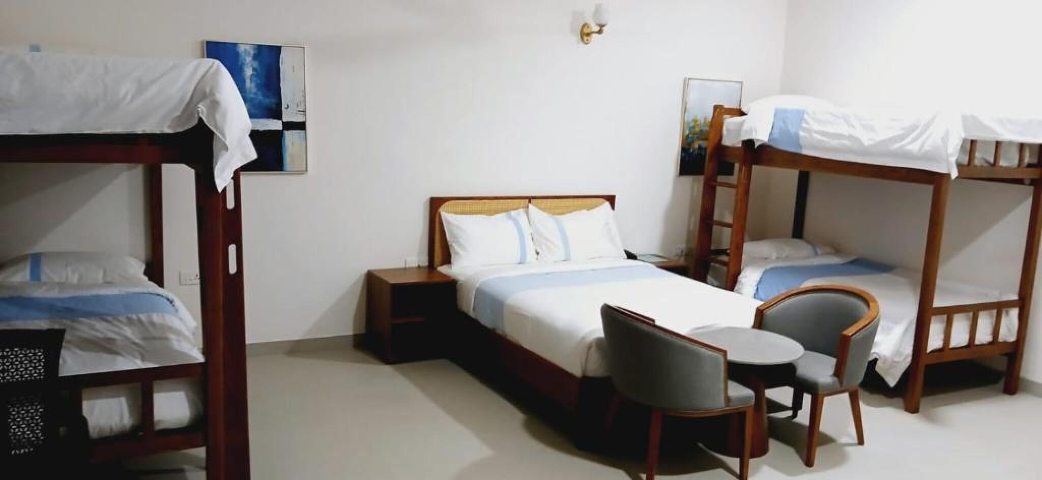 Una habitación con literas, una cama individual y una pequeña mesa con dos sillas.