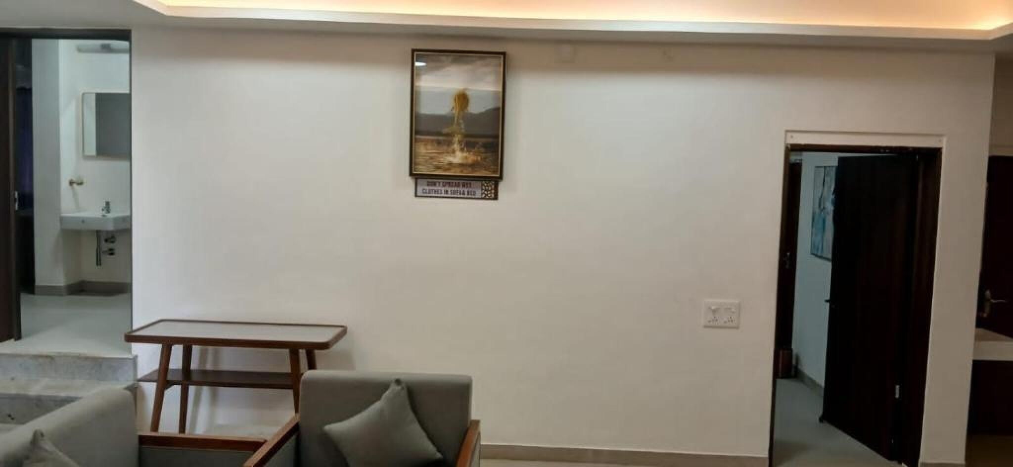 A modern living room with a sofa, a small wooden table, and a framed picture on the wall.