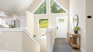 Una cocina amplia con armarios blancos, un refrigerador y una ventana con vistas a un paisaje verde.