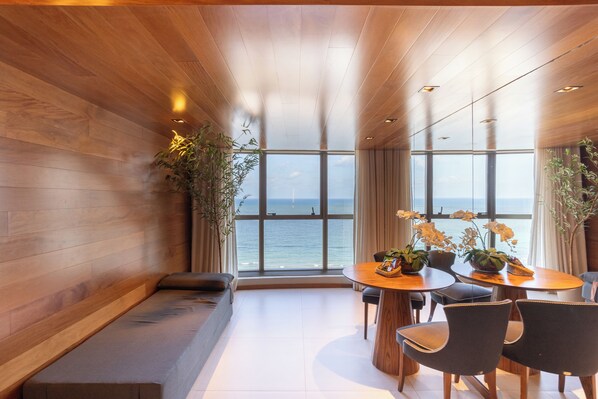 Une pièce moderne avec un plafond en bois, de grandes fenêtres, une table ronde en bois et un canapé.