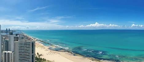 Un paisaje urbano costero con playa, edificios altos y cielos despejados.