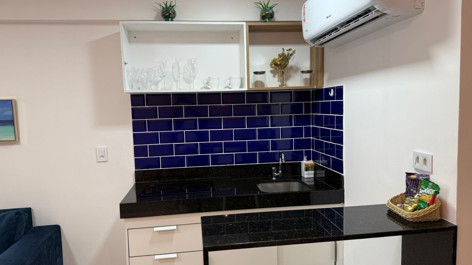 A kitchen with a black countertop, a sink, and a tiled backsplash.
