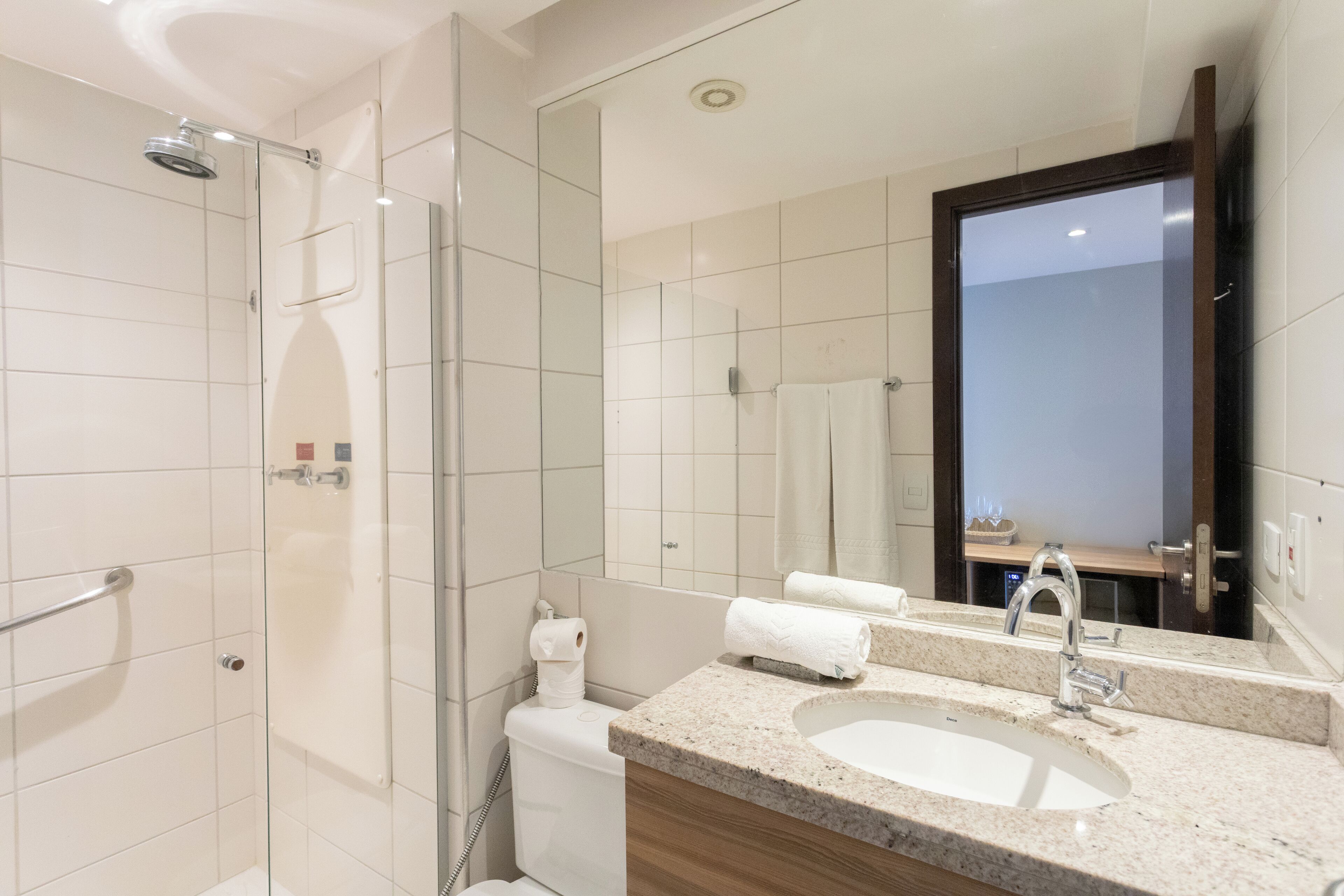 A modern bathroom with a glass shower enclosure, a sink with a vanity, and a large mirror.